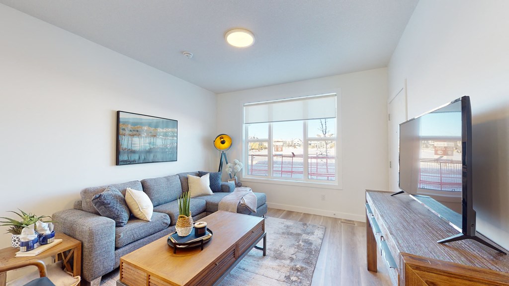 A living room with a grey couch, a wooden coffee table, and a flat screen TV.