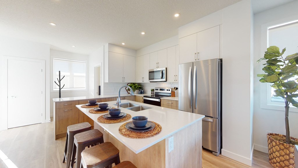 A modern kitchen with a white countertop and stainless steel appliances.