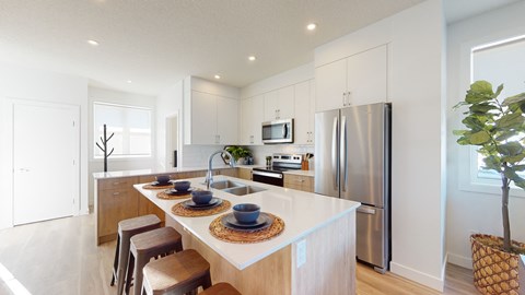 A modern kitchen with a white countertop and stainless steel appliances.