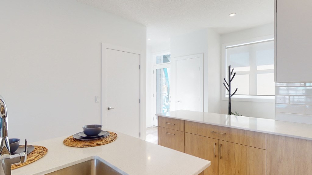 A modern kitchen with a white countertop and wooden cabinets.