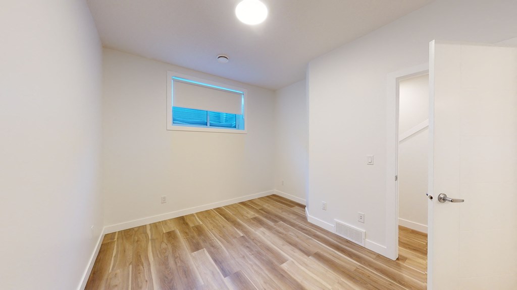 A room with a white door and a window with a blue sky reflection.