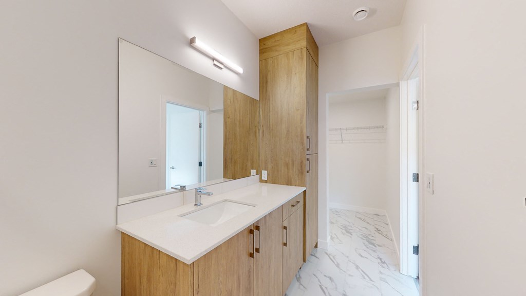 A bathroom with a sink, mirror, and wooden cabinetry.