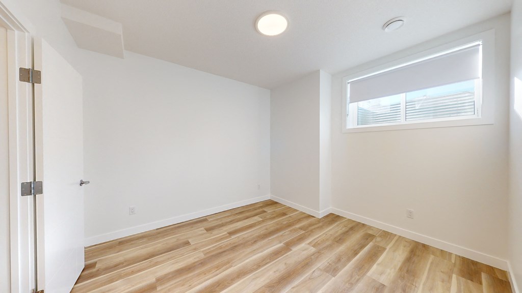 A room with wooden flooring and a window with blinds.