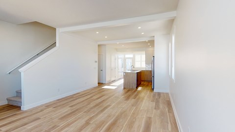 A spacious room with wooden flooring and white walls.