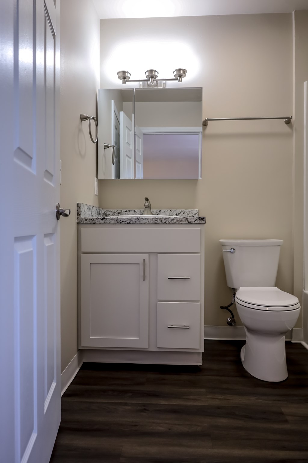 A white bathroom with a toilet, sink, and mirror.