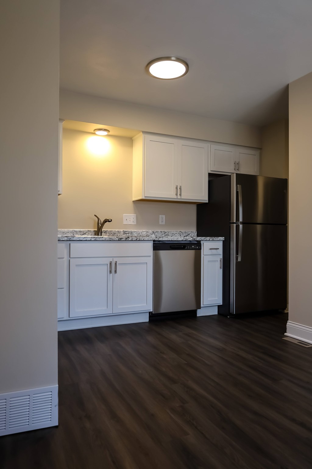 A kitchen with white cabinets and a black refrigerator.
