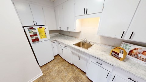A kitchen with white cabinets and a tiled floor.
