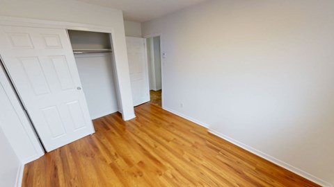 A room with a white door and wooden flooring.