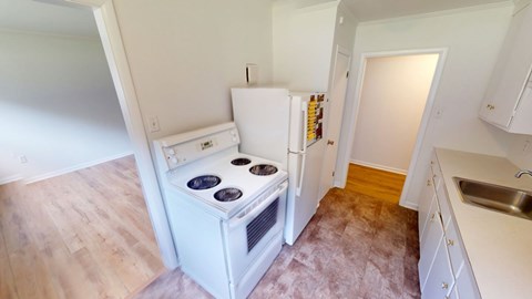 A white fridge and stove in a kitchen with wooden floors.