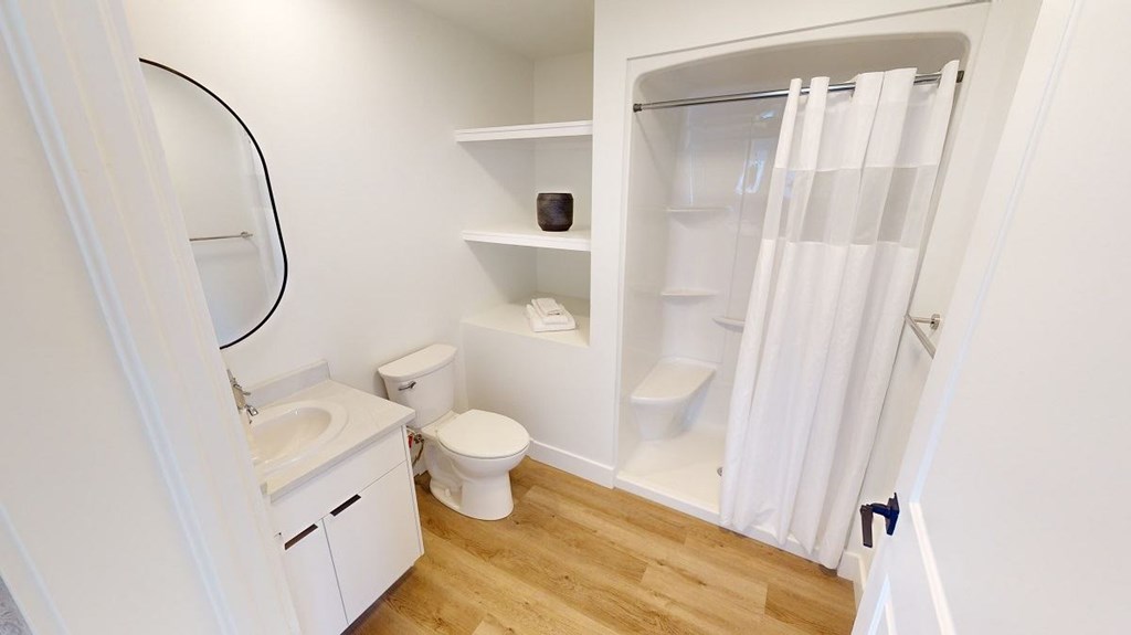 A white bathroom with a toilet, sink, and a shower with a white curtain.