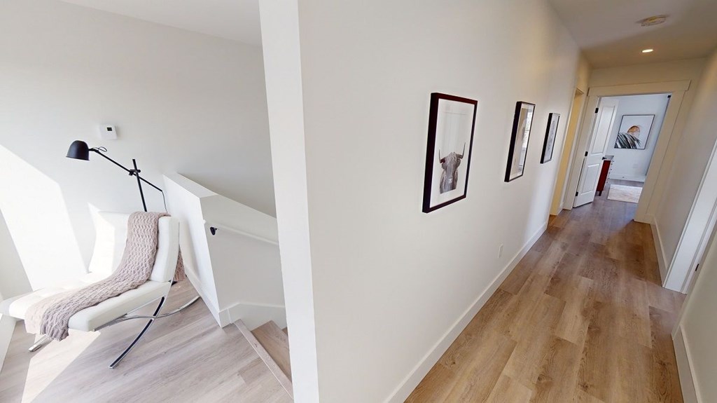 A hallway with a chair and pictures on the wall.
