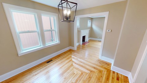 A room with wooden floors and a chandelier hanging from the ceiling.