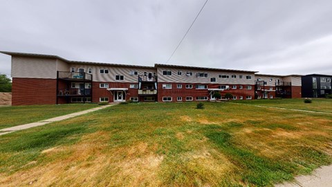 A large grassy area in front of a multi-story apartment building.