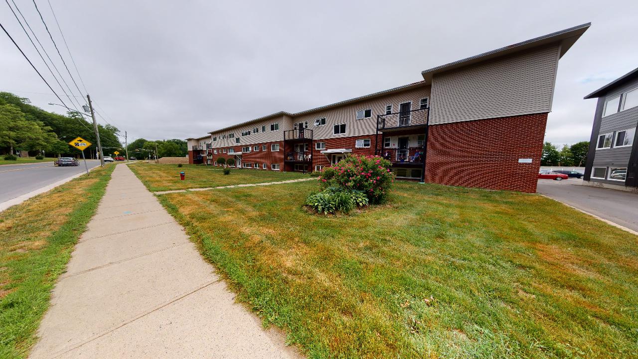 A long building with a red brick exterior sits next to a grassy area.