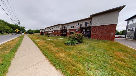 A long building with a red brick exterior sits next to a grassy area.