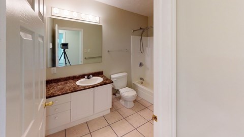 A bathroom with a sink, toilet, and a mirror.