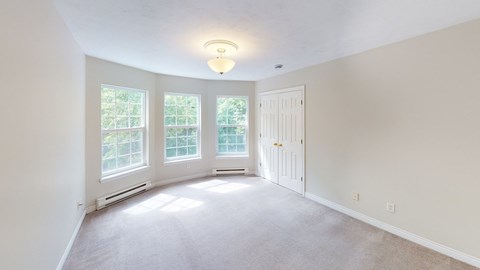 A room with a white door and a window with a view of trees.
