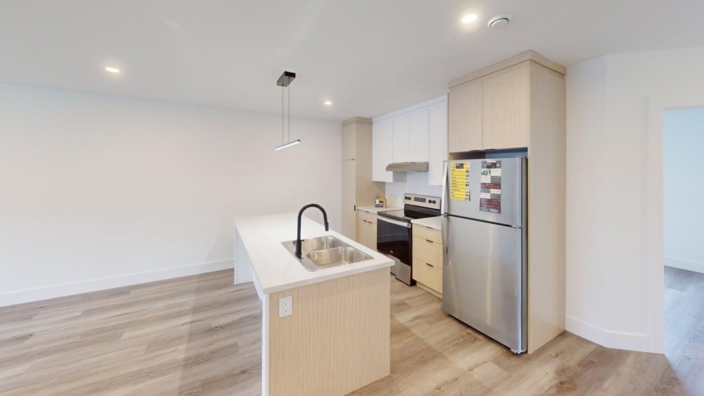 A kitchen with a sink, refrigerator, and cabinets.