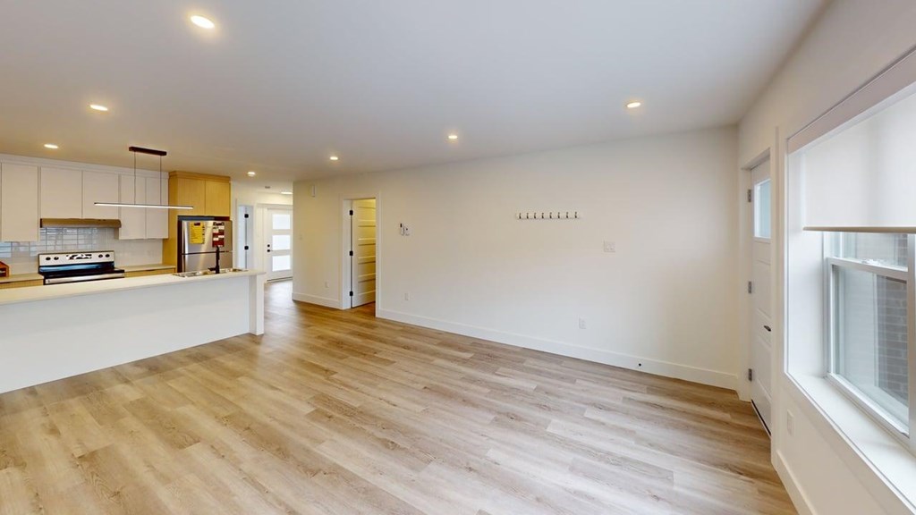 A spacious room with wooden flooring and white walls.