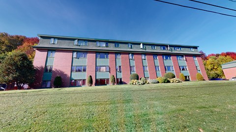 A red building with green trim and a green lawn in front.