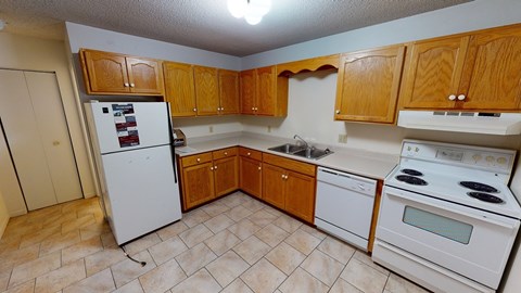 A kitchen with wooden cabinets and white appliances.