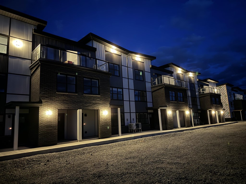 A row of modern townhouses are lit up at night.