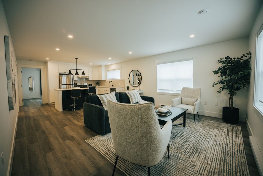 A modern living room with a black couch and a white chair.