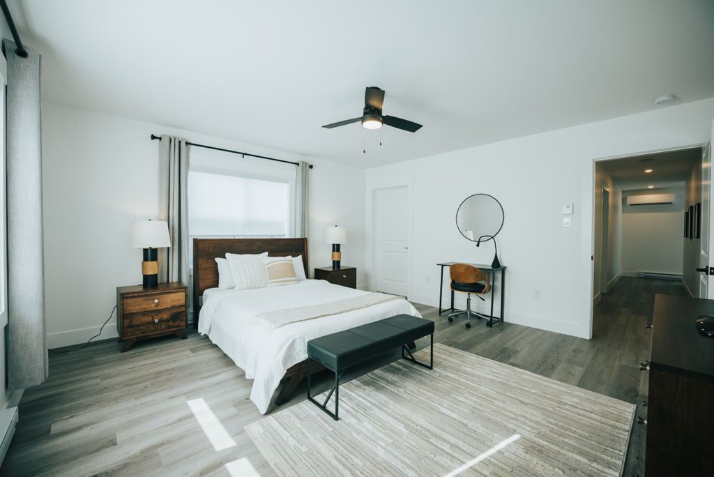 A bedroom with a bed, a chair, and a ceiling fan.