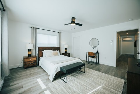 A bedroom with a bed, a chair, and a ceiling fan.