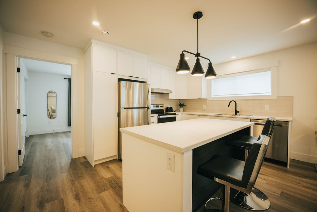 A kitchen with a white counter and a black chair.