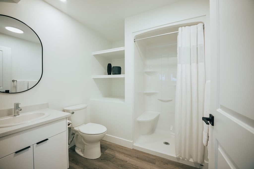 A white bathroom with a toilet, sink, and shower.
