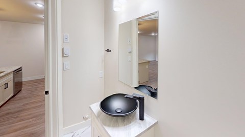 A bathroom with a black bowl sink and a mirror.