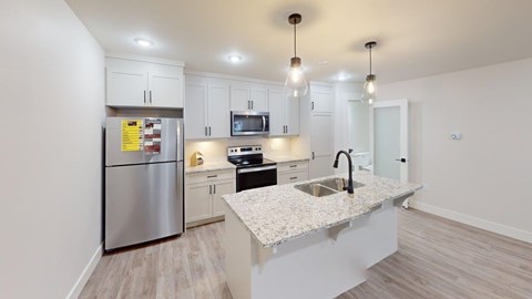 A modern kitchen with a stainless steel refrigerator, microwave, and sink.