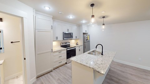 A kitchen with a granite countertop and a microwave above it.