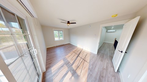 A room with a sliding glass door and a ceiling fan.