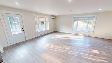 A spacious room with wooden floors and white walls.