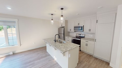 A kitchen with white cabinets and a granite countertop.