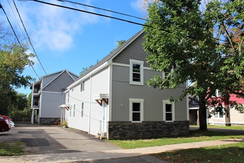 A grey house with a red car parked in front.