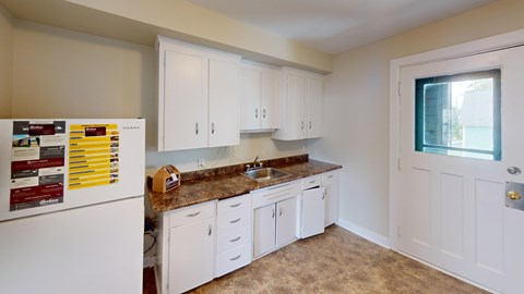 A kitchen with white cabinets and a white fridge.