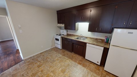 A kitchen with brown cabinets and white appliances.