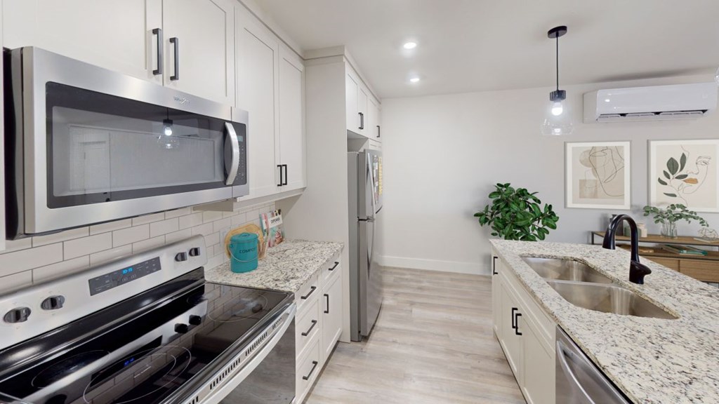 A modern kitchen with stainless steel appliances and a marble countertop.