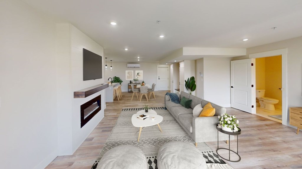 A modern living room with a grey sofa, a coffee table, and a TV mounted on the wall.