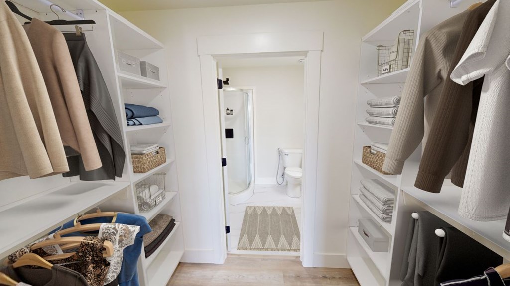 A walk-in closet with clothes and towels.