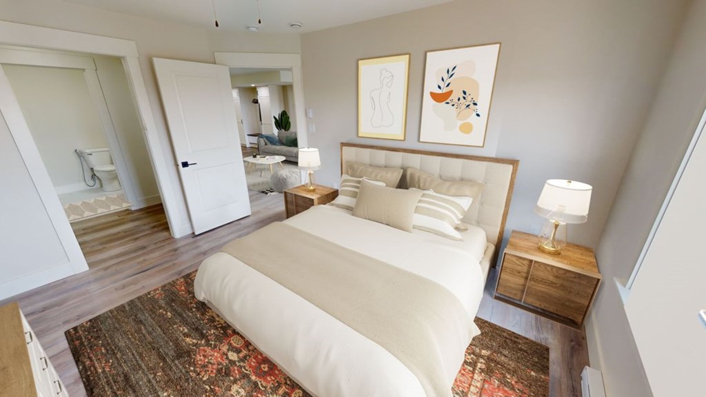 A bedroom with a large bed and a rug on the floor.