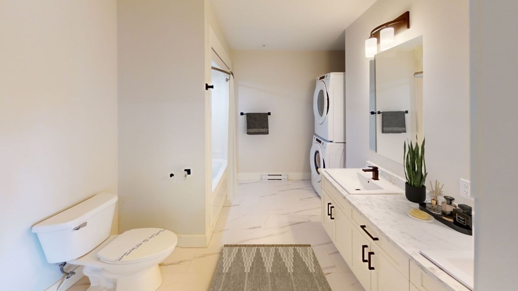 A white bathroom with a toilet, sink, and mirror.