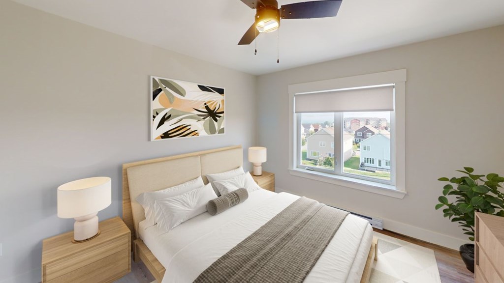 A bedroom with a bed, a ceiling fan, and a window with a view of a residential area.