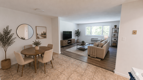 A living room with a round table and chairs, a television, and a rug.