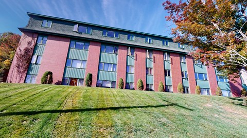 A red building with green shutters and a grey roof.