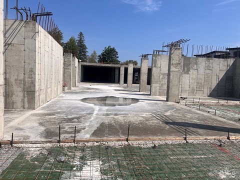 A construction site with a large open space in the middle and a concrete wall on the left side.