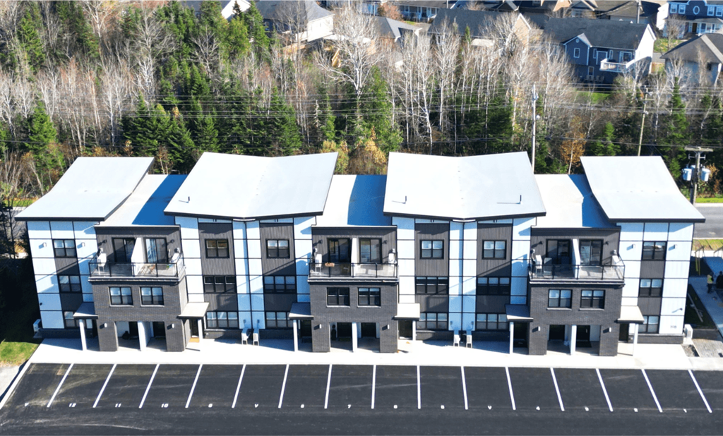 A parking lot in front of a building with grey and white exterior.